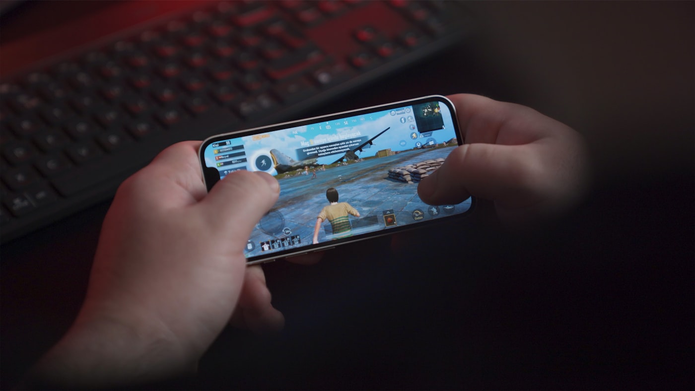 Deux mains tenant un smartphone sur lequel tourne un jeu vidéo